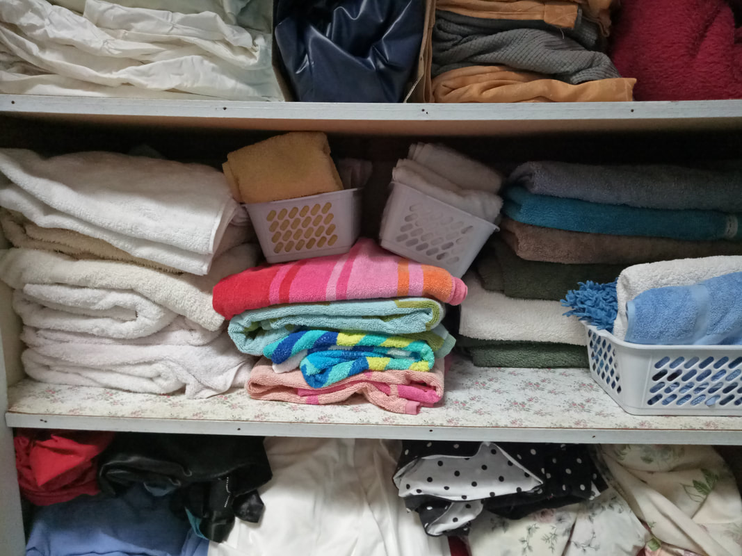 Photo of a linen cupboard with a shelf holding three piles of folded towels