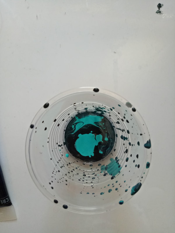 Picture of a cup with black and turquoise paint in it